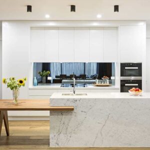 Modern minimalist kitchen in Mont Albert with white handleless cabinetry, stone island and timber table