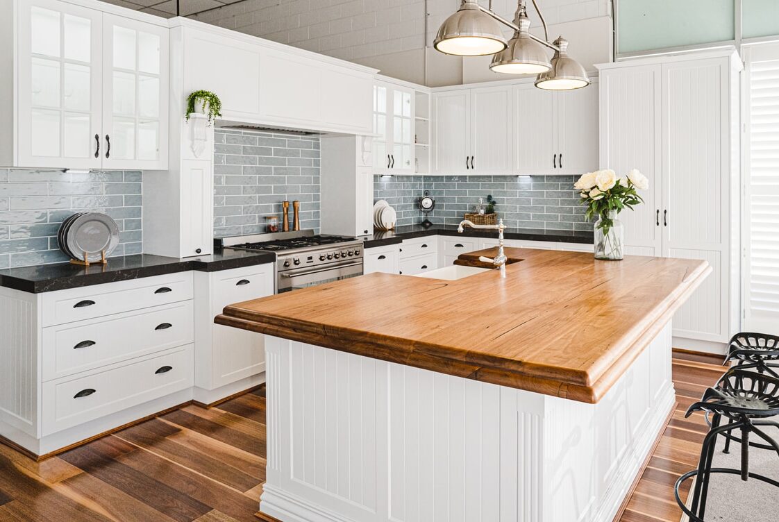 French provincial kitchen with white cabinetry, timber island benchtop and grey subway tile splashback