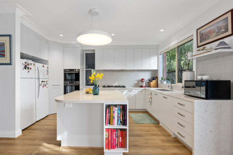 Modern white kitchen renovation in Canterbury with island bench, handleless cabinetry and timber flooring